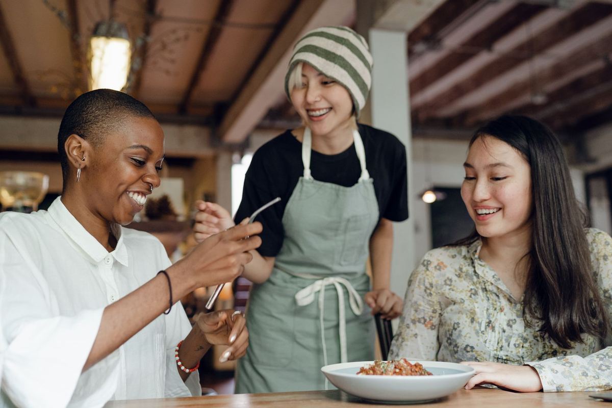 A support worker helping someone in their kitchen while family look on